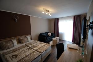 a bedroom with a bed and a chair and a television at Schenk´s Landgasthof in Amorbach