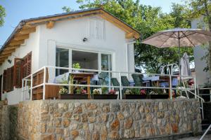 a house with a balcony with chairs and an umbrella at Simple beachfront rooms Bego in Kraljevica