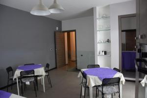 dwa stoły i krzesła w pokoju z fioletową tkaniną w obiekcie Casa Natia w mieście Favara