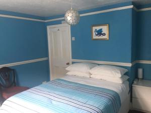 a bedroom with blue walls and a bed with white pillows at Circles Guest House in Pewsey
