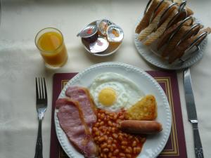 a plate of breakfast food with eggs bacon beans and toast at Weybourne Guest House in Tenby