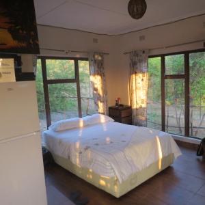 a bedroom with a large bed in a room with windows at Mount Hermon Safari Cottages in Chaledzela