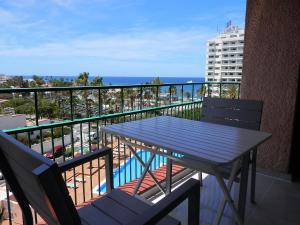 una mesa y sillas en un balcón con vistas al océano en Apartamentos Acapulco, en Playa de las Américas