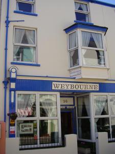 een wit gebouw met blauwe afwerking en een zeer boetiek bij Weybourne Guest House in Tenby