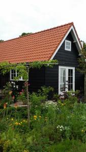 a black house with a red roof and a garden at 't Hofhuys Oss in Oss