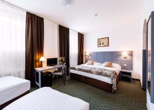 a hotel room with two beds and a desk at Central Hotel Prague in Prague