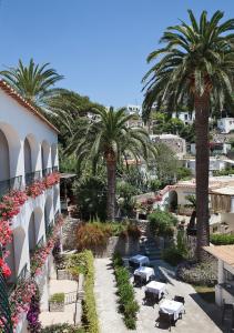 a view of a resort with palm trees and tables at Hotel Della Piccola Marina in Capri