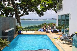 eine Gruppe von Menschen, die um einen Pool herum sitzen in der Unterkunft Sea view guest house in Auckland