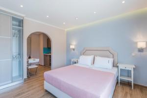 a bedroom with a white bed and a bathroom at Pansion Ermioni in Skala