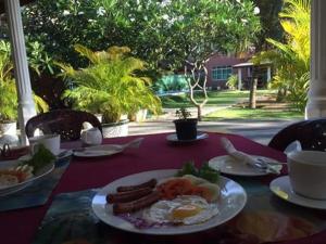 a table with a plate of food with eggs and sausage at Larn's Villa Hotel & Apartment in Wadduwa