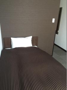 um quarto com uma cama com um cobertor listrado em Atsugi Hotel Yugiri em Atsugi