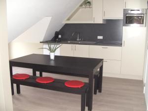 a kitchen with a black table and red seats at 't Vossenerf in De Haan