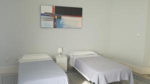 - 2 lits dans une chambre avec une photo sur le mur dans l'établissement Pensión Santa Paula, à Malaga