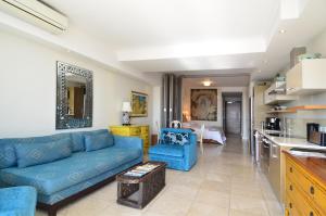 a living room with a blue couch and a kitchen at 702 Canal Quays in Cape Town