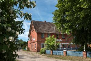 ein rotes Backsteingebäude mit einem blauen Zaun in der Unterkunft Frühstückspension Landhaus Lange in Prerow