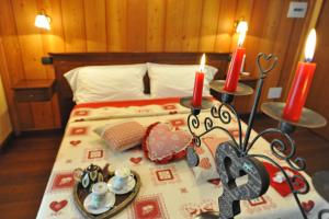 1 dormitorio con 1 cama con 2 velas y un plato de comida en L'Ancien Paquier Chambre D'Hotes, en Valtournenche