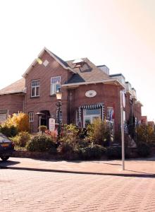 a brick building on a street with a car in front at Pension Corper in Zandvoort