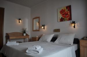 a bedroom with a white bed with towels on it at Byzance Hotel in Skala