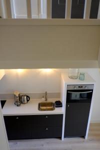 een kleine keuken met een wastafel en een magnetron bij Huisje aan de gracht in Franeker