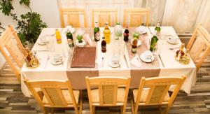 une table avec un tissu de table blanc, des bouteilles et des chaises dans l'établissement Семеен Хотел Вит, à Teteven