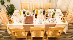 テテヴェンにあるСемеен Хотел Витの白いテーブルクロスとボトルと椅子付きのテーブル