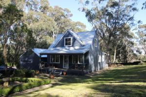 a black house with a gambrel roof at Cottage At 31 in Bundanoon