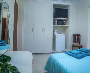 a white room with a bed and a kitchen at Lientjies Overnight in George