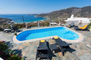 - une piscine avec des chaises et une vue sur l'océan dans l'établissement Villa Pelagos, à Platis Gialos