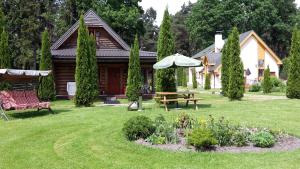 una casa con una mesa de picnic y una sombrilla en el patio en Forest Edge Lodge en Riga