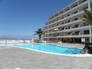 a swimming pool in front of a large apartment building at Beach Apartment with Ocean View La Arena in Puerto de Santiago