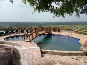a large pool with a wooden bridge over it at Lobo Wildlife Lodge in Serengeti