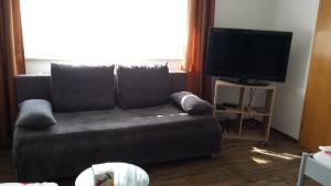 uma sala de estar com um sofá e uma televisão de ecrã plano em Ferienwohnung Baur em Tussenhausen