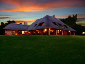 a large house with a roof on a grass field at African Footprints Lodge in Midrand