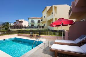 a swimming pool with a red umbrella and a building at Elite City Resort in Kalamata