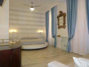 a bedroom with a bed and a mirror and blue curtains at Suites Margot in Santa Margherita Ligure