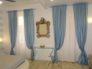 a bedroom with blue curtains and a mirror at Suites Margot in Santa Margherita Ligure