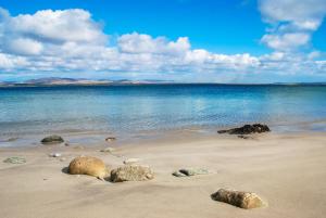 a beach with rocks in the sand and water at Port Charlotte Hotel in Port Charlotte