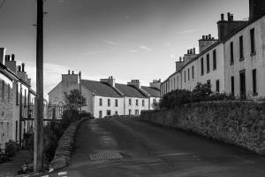 a black and white photo of a street with houses at Port Charlotte Hotel in Port Charlotte
