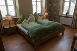 a bedroom with a bed with green sheets and windows at Dooscht Gästehaus Reichshof in Kröv