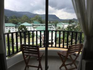 2 stoelen op een balkon met uitzicht op de stad bij Skylight Apartment in Nuwara Eliya