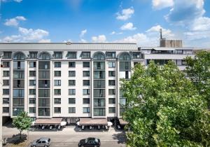 a large white building with cars parked in front of it at Downtown Vi Vadi Hotel in Munich