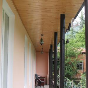 a porch with a wooden ceiling and a table and chairs at Tvishi Guest House in Tsʼageri