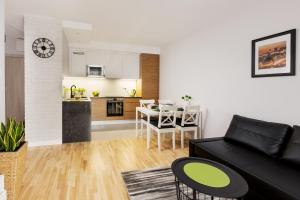 a living room with a black couch and a kitchen at Millennium Manufaktura Green in Warsaw