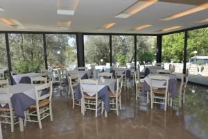 a restaurant with white tables and chairs and windows at Phaistos Hotel in Tolo