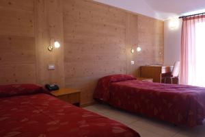 ein Hotelzimmer mit 2 Betten und einem Tisch in der Unterkunft Hotel La Rosa in Teglio