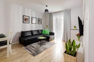 a living room with a black couch and a table at Millennium Manufaktura Green in Warsaw