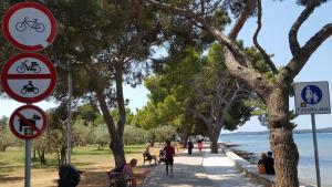 a sidewalk next to a body of water with street signs at Apartment Luka in Fažana