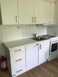 a kitchen with white cabinets and a sink and a stove at Hybeltunet in Meråker