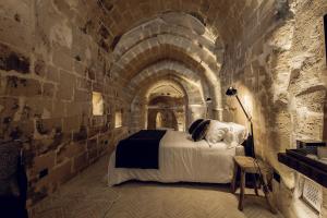 - une chambre avec un lit dans un mur en pierre dans l'établissement Palazzotto Residence&Winery, à Matera