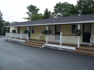 a small yellow house with a porch and white railing at Drake's Island Resort & Cottages in Wells